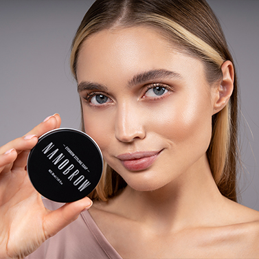 Uma mulher de olhos azuis segurando o sabonete modelador na frente do rosto